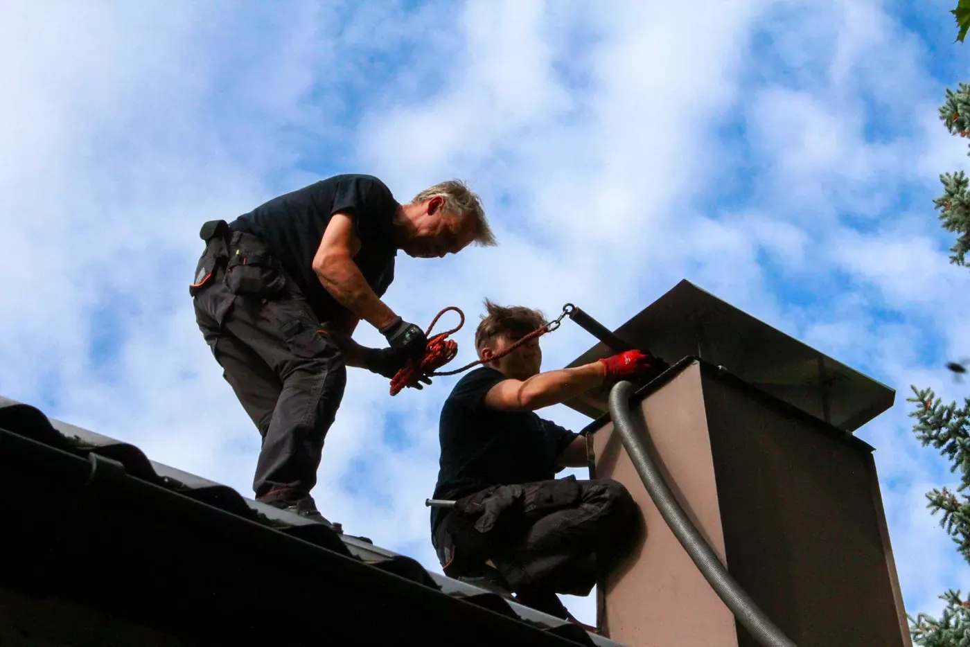 Ammattitaitoiset nuohoojat työssään katolla